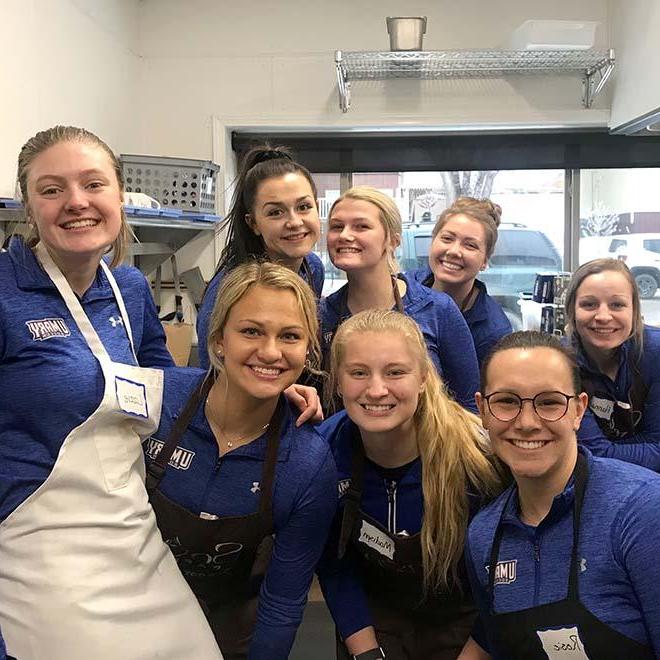 Eight female soccer players volunteering at soup kitchen